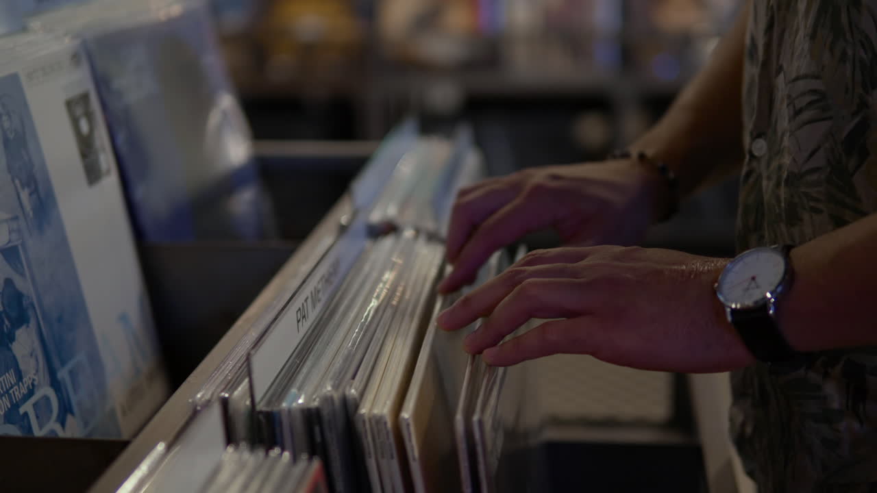 cliente masculino mirando a través de discos de vinilo que se muestran en una tienda de discos de música