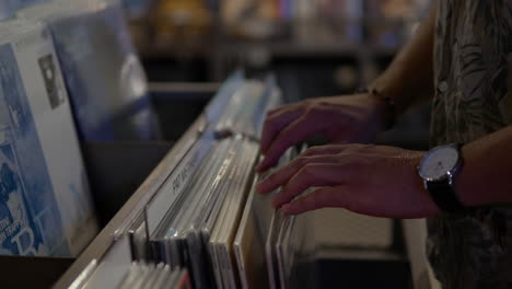 Male-Customer-Looking-Through-Vinyl-Records-Displayed-In-A-Music-Record-Store