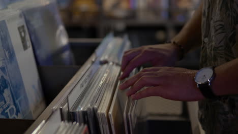 male customer looking through vinyl records displayed in a music record store