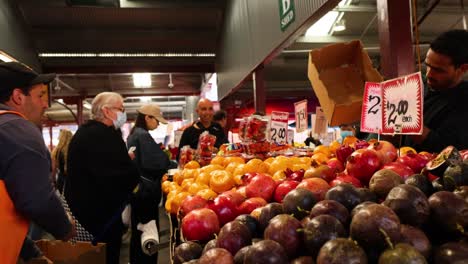 vendor arranging and selling fruits at market stall