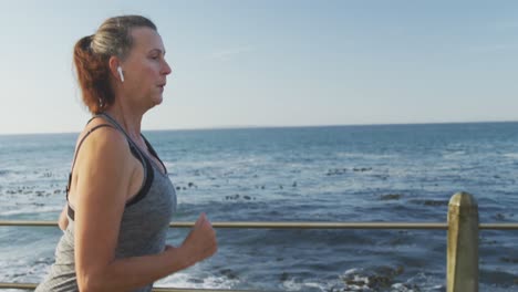 mujer mayor corriendo en un paseo marítimo