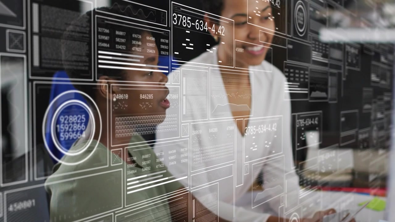 Lead leaning, pointing at monitor, urging analyst typing to review data while HUD charts overlaying