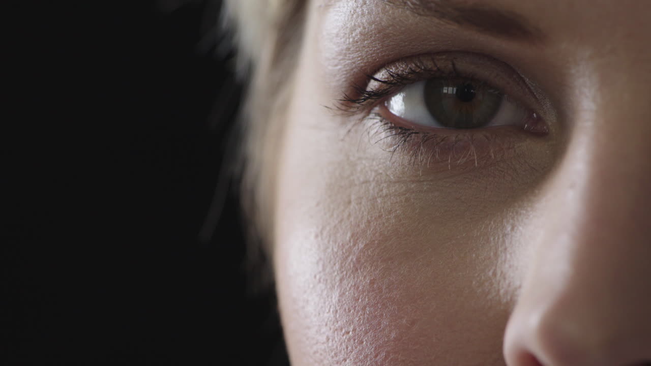 젊은 여성의 눈이 카메라를 바라보며 웃고 행복하게 검은 바탕에 고립되어 있습니다.