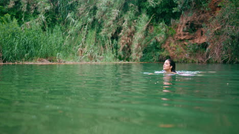 lonely girl swimming pond green nature. focused woman resting in amazing lake