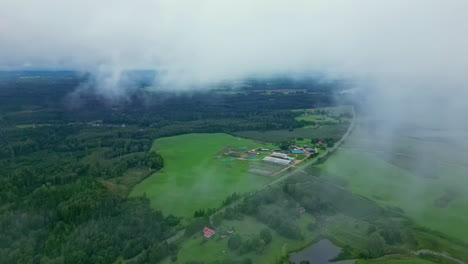 volando a través de la niebla y las nubes para revelar exuberantes tierras de cultivo y una aldea