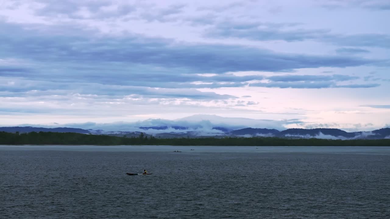 Wewak Papua New Guinea fishing fishermen outrigger canoe early morning aerial drone rain clouds mist fog Dogreto Bay Cape Wom tropical island coastline ocean sea waves swell forward pan left