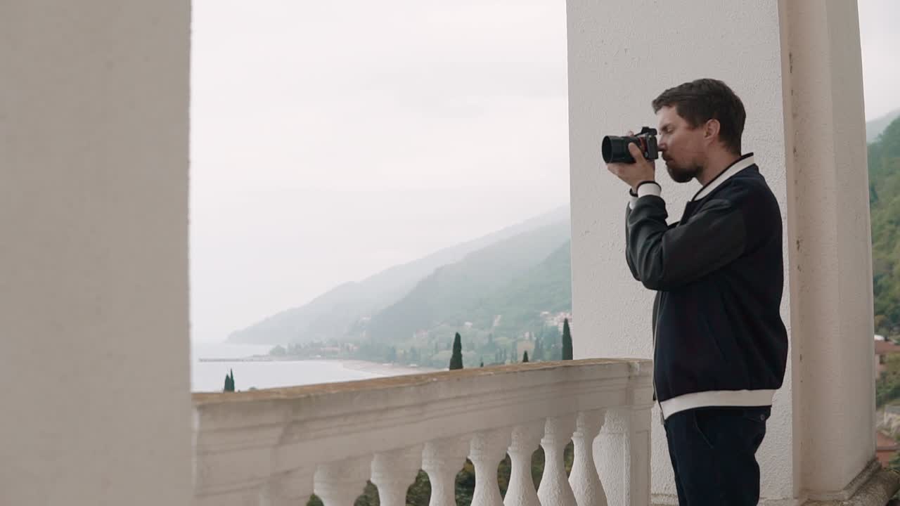 hombre tomando una foto de la vista del mar desde el balcón