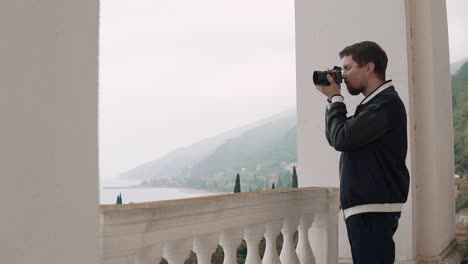 hombre tomando una foto de la vista del mar desde el balcón