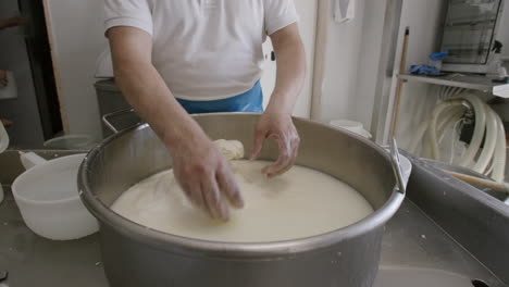 un quesero en italia tirando y doblando y estirando un gran lote de mozzarella