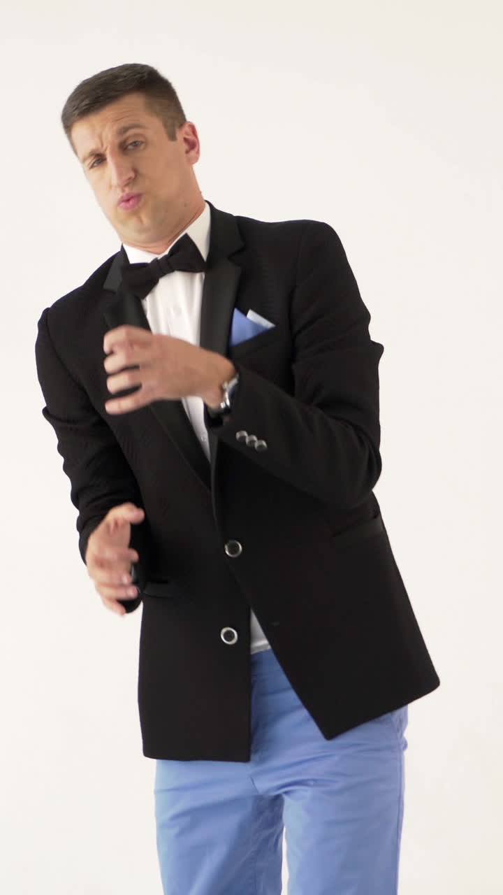 fun showman in black jacket is showing how a trumpet player plays a trumpet at concert on a white background in the studio Vertical video