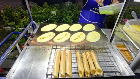 vendor prepares mini pancake rolls in bangkok