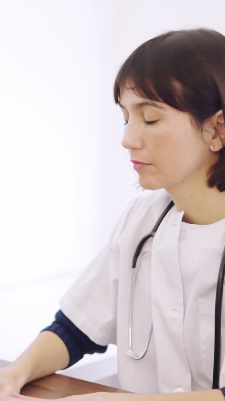 Doctor using computer sitting on a desk in a clinic