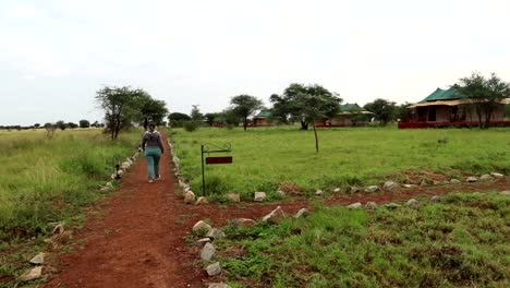 panning right shot on the camp sight as a woman walking away on a dirt path pass a street sign