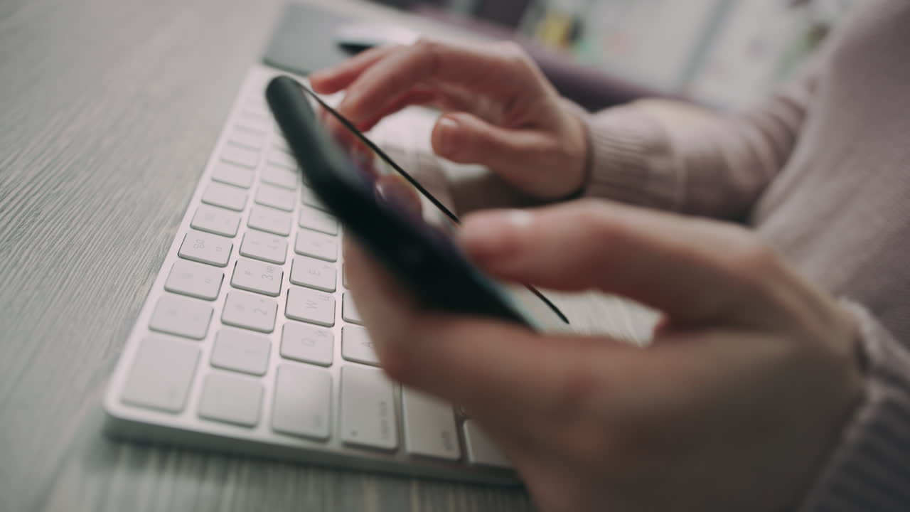 Female hands typing on computer keyboard. Woman hands texting on mobile phone