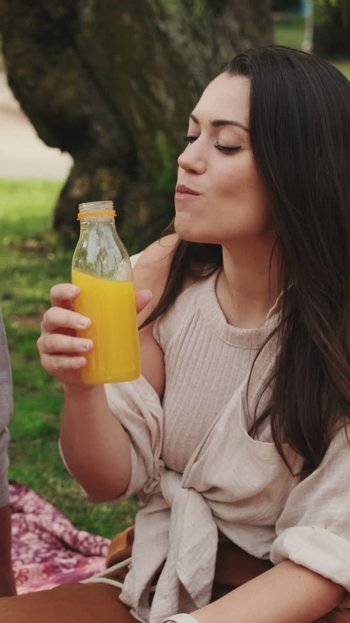 Mujer bebiendo zumo de naranja en el parque