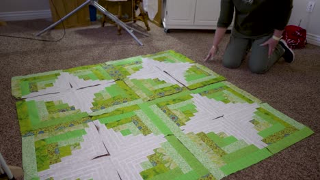 a senior caucasian woman completes the final arrangement of her quilt blocks