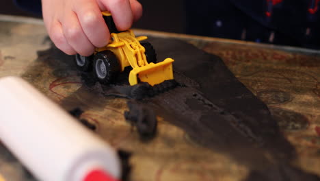 a close-up of a child's hands playing with his tow digger and clay inside during lockdown