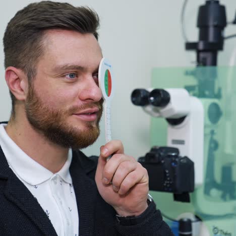 young man at ophthalmologist's. checking eyesight in clinic. patient closing one eye to test his vision. optical concept