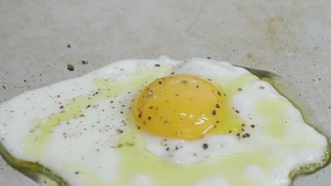 primer plano de un huevo frito a la parrilla mientras se agrega aceite de cocina al huevo