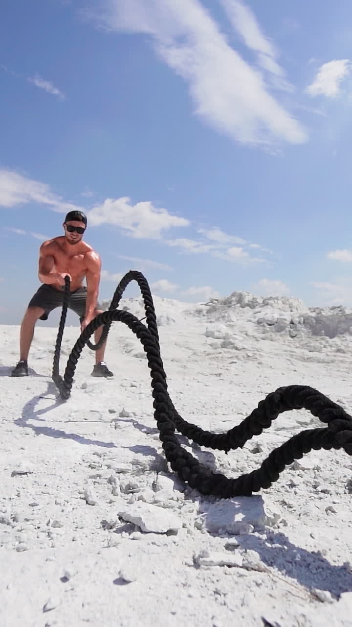 Entraînement d'homme en pleine nature. Homme sportif faisant des exercices avec des cordes de combat. Vidéo verticale.