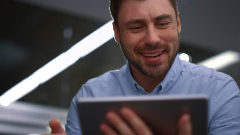 hombre de negocios alegre videochatando en línea hablando tableta en la corporación de finanzas