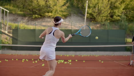 Eine-Tennisspielerin-übt-Das-Schlagen-Des-Balls,-Während-Der-Trainer-In-Zeitlupe-Mit-Einem-Schläger-Auf-Den-Ball-Schlägt.-Training-Einer-Professionellen-Tennisspielerin.