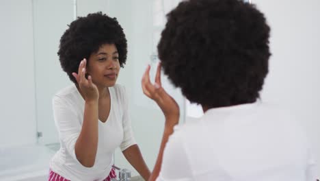 Mujer-Afroamericana-Tocándose-La-Cara-Mientras-Se-Mira-En-El-Espejo-Del-Baño