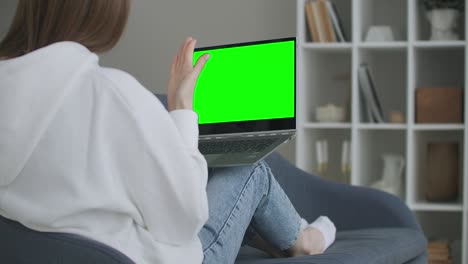 mujer en casa sentada en un sofá trabaja en una computadora portátil con pantalla de maqueta verde. educación remota de cuarentena de coronavirus covid-19 o concepto de trabajo. niña usando computadora, navegando a través