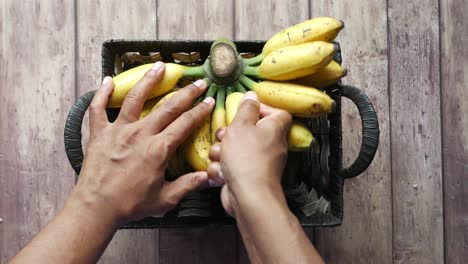hands picking bananas from a basket