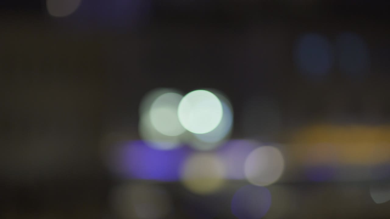luces nocturnas desfocadas de la ciudad en el distrito comercial de parís. bokeh borroso de colores de los edificios. inclinarse hacia abajo y luego desplazarse hacia la derecha. 4k uhd.