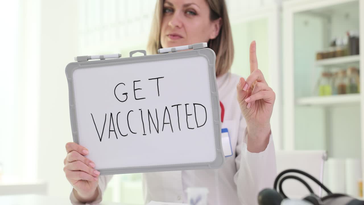 Woman holding 'GET VACCINATED' sign and pointing