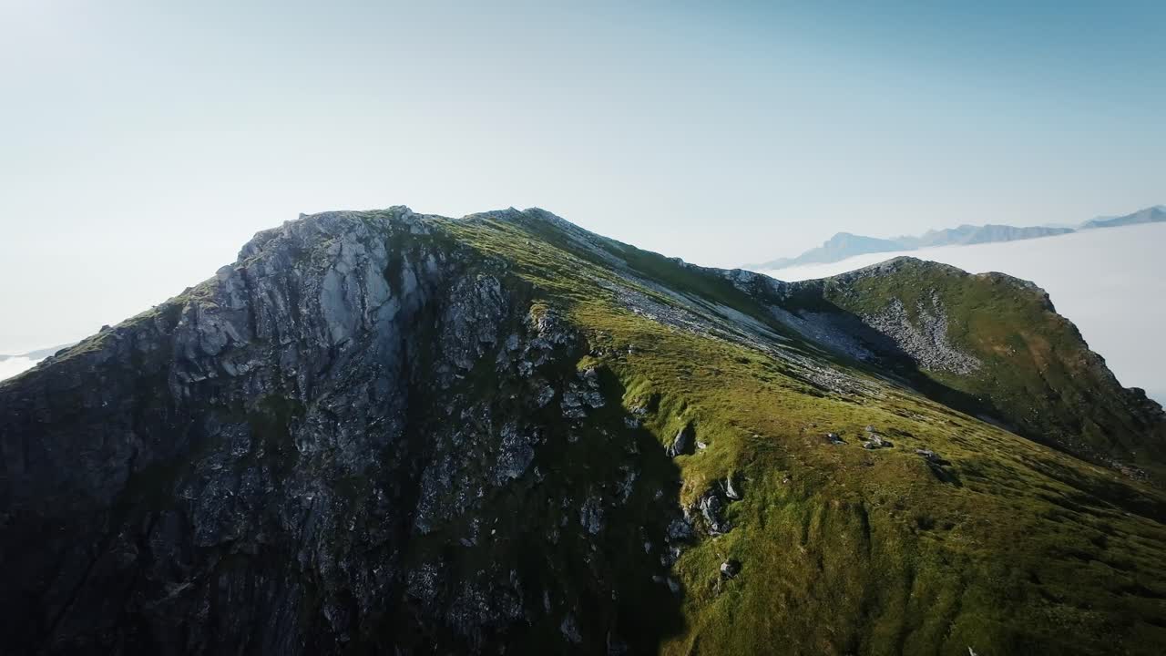 Filmisk FPV-droneskud, stabiliseret fra Lofoten, der afslører Norges skybeklædte landskab bag bjerget