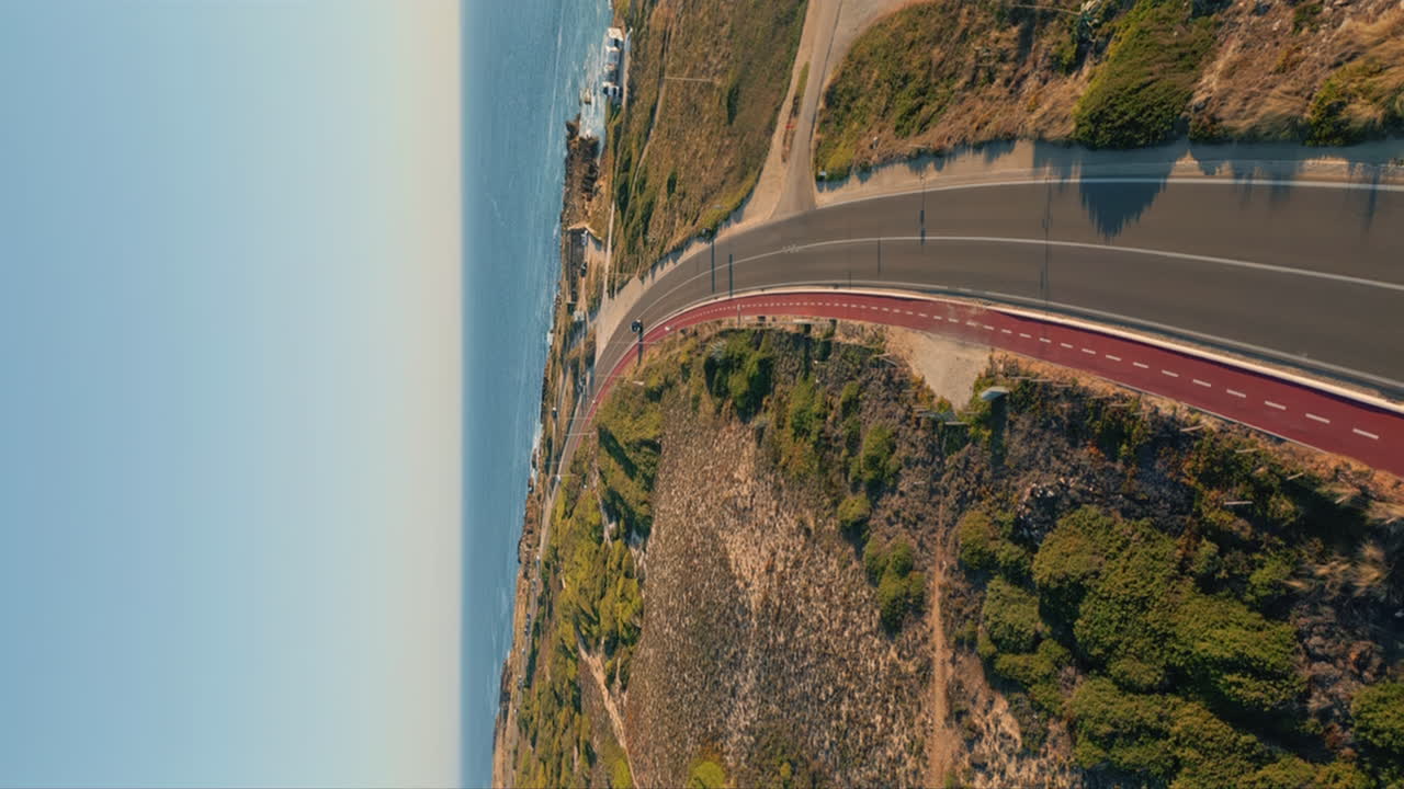 Scenic road running seaside under blue sky aerial view. Straight asphalt highway