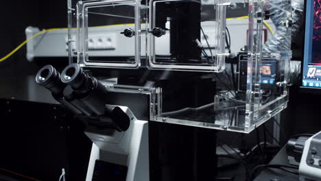 baje a un modelo de microscopio moderno con una caja de plexiglás para sostener el espécimen