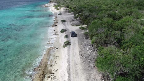 一辆汽车在岛屿上靠近海洋驾驶无人机视图