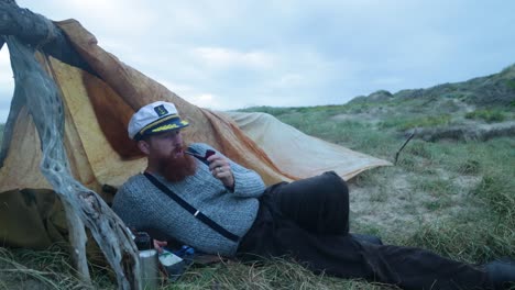 1900s sailor smoking a pipe by his makeshift camp along the coast