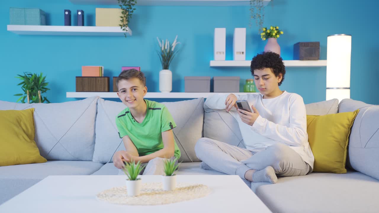 el hermano menor ve un programa de televisión que no es apropiado para su edad.