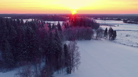 sunset over a snowy winter countryside - aerial flyover