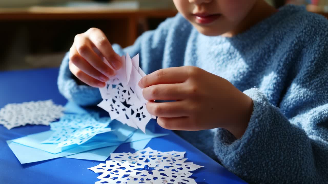 Child Engaged in Creative Paper Crafting, Skillfully Cutting and Assembling Intricate Snowflake Designs with Blue and White Paper Components