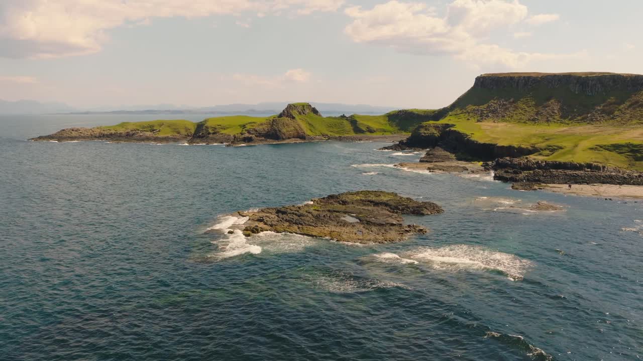 Aerial drone footage of dramatic sea cliffs along the rugged Scottish coastline on the Isle of Skye. Towering rock formations, crashing waves, and breathtaking views