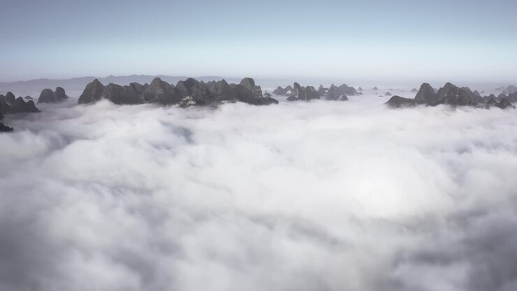 Aerial: mountaintops rising above clouds, low cloud cover in mountain valley