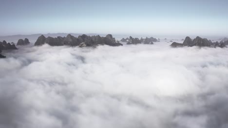 aerial: mountaintops rising above clouds, low cloud cover in mountain valley