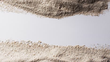 Video-of-close-up-of-sand-grains-and-copy-space-on-white-background