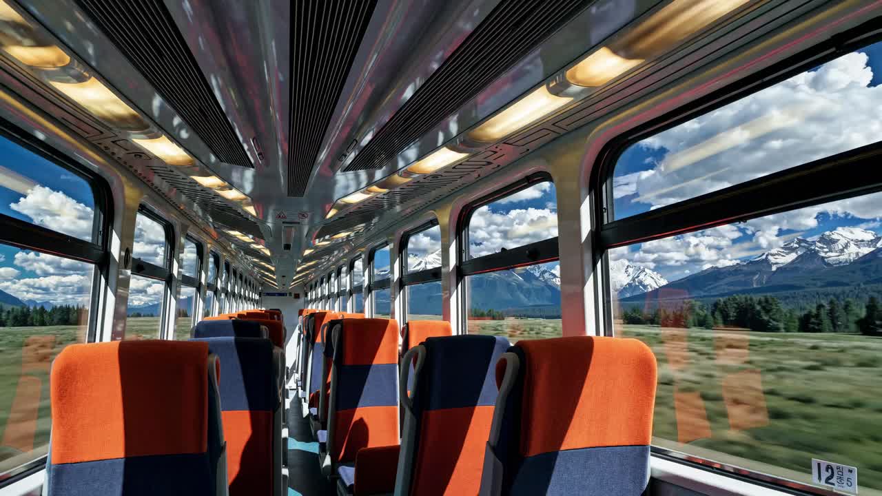 Wide-angle view from inside a train with orange seats, capturing scenic landscapes through windows