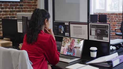 mujer caucásica en chat de video portátil sentada en el escritorio en la oficina