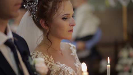 the bride and the groom stand in church, holding candles in their hands