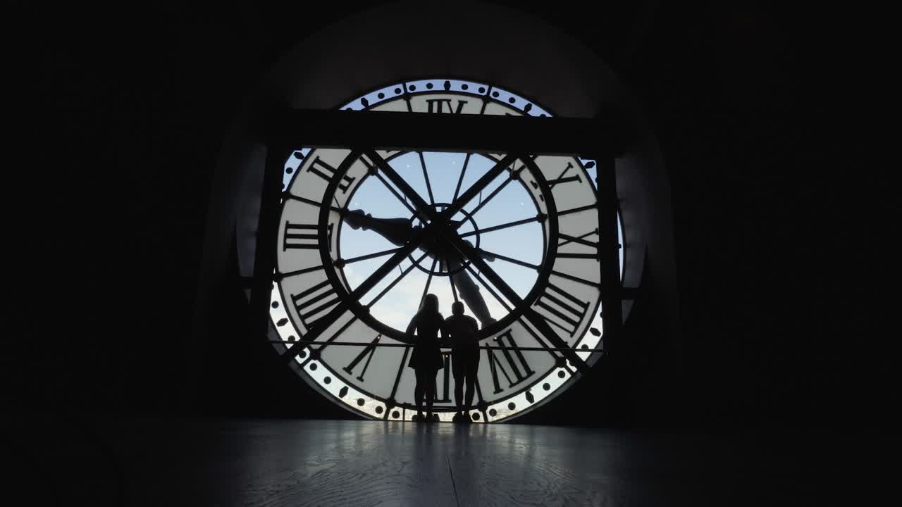 Couple silhouette kissing in front of a clock in Orsay museum, Paris France