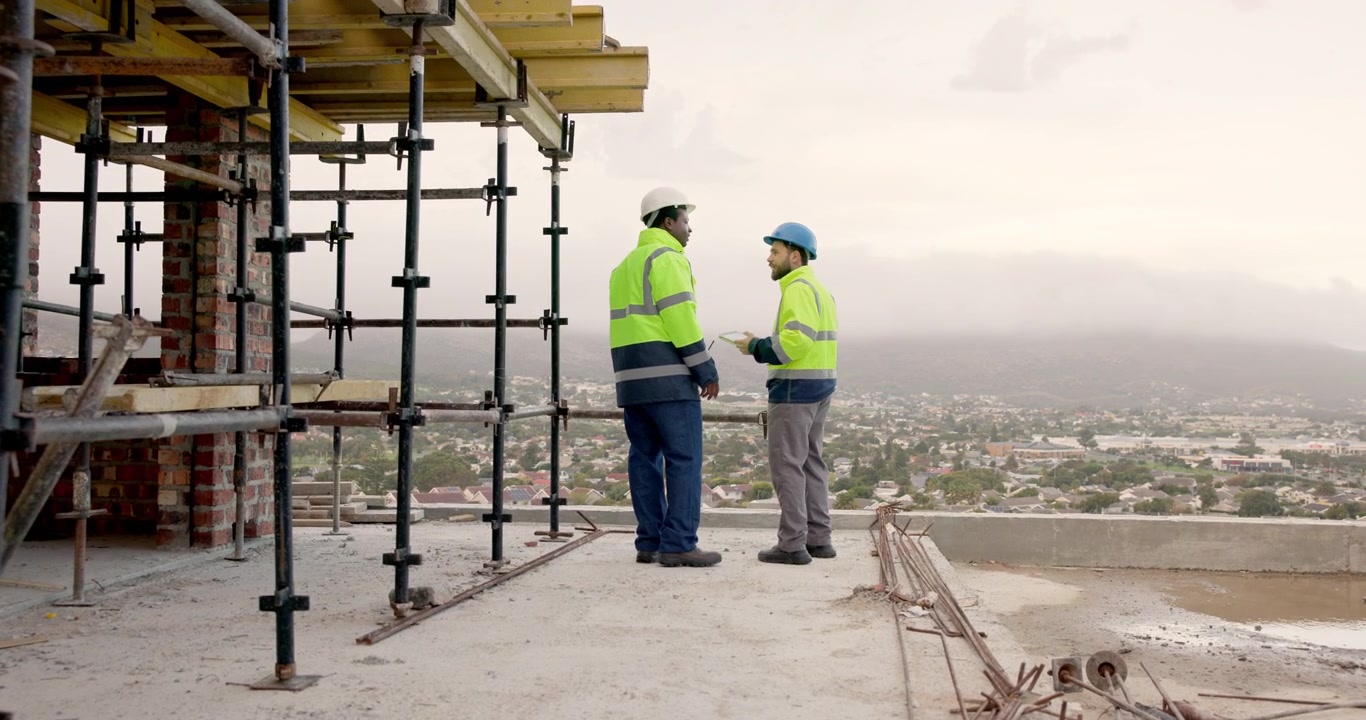 Two Construction Workers Discussing Project Plans on Building Site