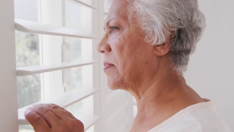Ältere-Afroamerikanische-Frau-Blickt-Zu-Hause-Auf-Ihr-Fenster