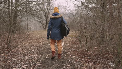 a young woman with short hair takes a walk with her dog in the woods 3